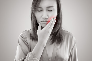 Suffering from toothache. Beautiful young woman suffering from toothache while standing against...