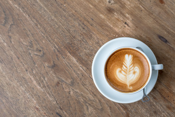 Hot Coffee Latte in white cup with water in a glass on the wooden table with space in the left side