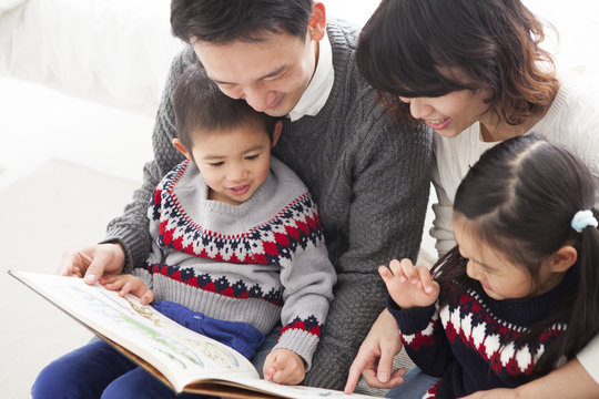お父さん、お母さんと一緒に、絵本を読んでいる男の子と女の子。