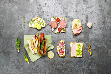 Sandwiches from a variety of ingredients on a gray concrete surface. Top view.