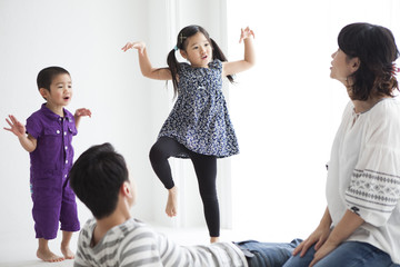 Obraz premium 歌って、踊っている女の子と男の子。笑顔で見守るお父さんとお母さん。