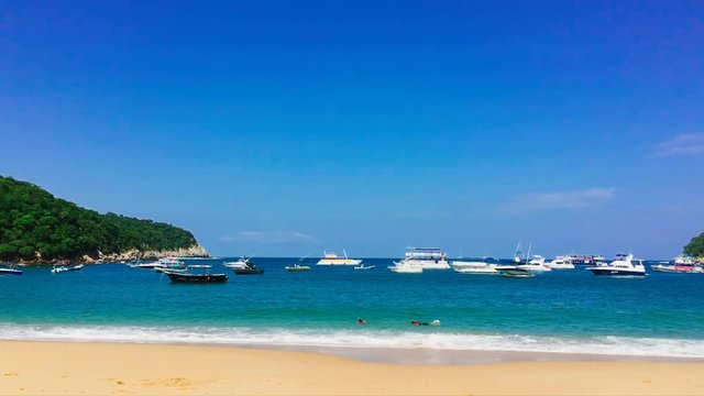 Snorklers and yachts in the bay at Playa el Maguey, Oaxaca, Mexico.