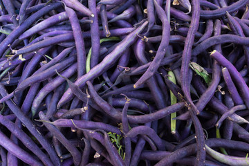 Multiple purple green beans for sale in a bin at a farmers' market in Aix en Provence, France.