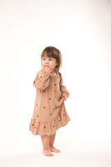 Cute little girl in beige dress isolated on white background. Portrait of happy little girl on white background. Sweet girl with curly hair.