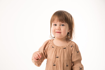 Cute little girl in beige dress isolated on white background. Portrait of happy little girl on white background. Sweet girl with curly hair.