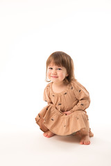 Cute little girl in beige dress isolated on white background. Portrait of happy little girl on white background. Sweet girl with curly hair.