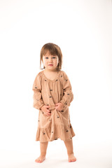 Cute little girl in beige dress isolated on white background. Portrait of happy little girl on white background. Sweet girl with curly hair.