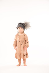 Portrait of happy little girl. Cute little girl in beige dress in a gray hat isolated on white background.