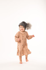 Portrait of happy little girl. Cute little girl in beige dress in a gray hat isolated on white background.