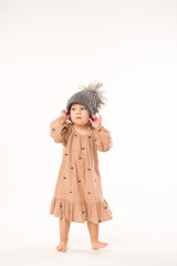 Portrait of happy little girl. Cute little girl in beige dress in a gray hat isolated on white background.