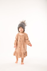 Portrait of happy little girl. Cute little girl in beige dress in a gray hat isolated on white background.