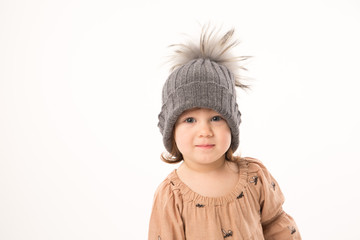 Portrait of happy little girl. Cute little girl in beige dress in a gray hat isolated on white background.