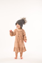 Portrait of happy little girl. Cute little girl in beige dress in a gray hat isolated on white background.
