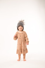Portrait of happy little girl. Cute little girl in beige dress in a gray hat isolated on white background.