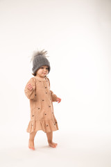 Portrait of happy little girl. Cute little girl in beige dress in a gray hat isolated on white background.