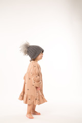 Portrait of happy little girl. Cute little girl in beige dress in a gray hat isolated on white background.