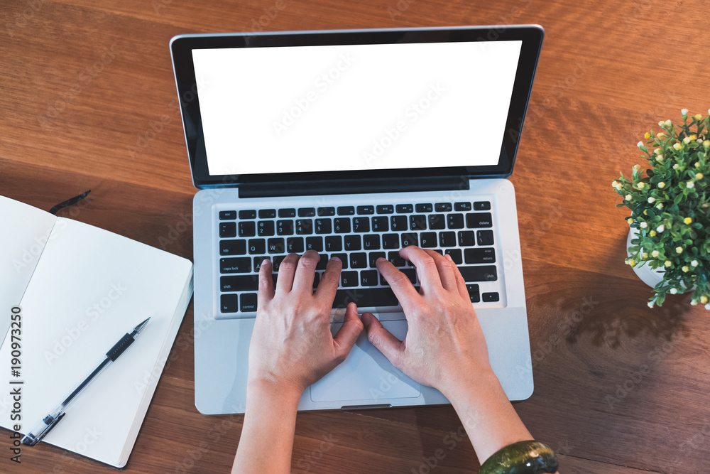 Poster top view hand type on laptop keyboard with open notebook and plant on table at home.mock up screen for display of design or content.clipping path screen.working with technology.