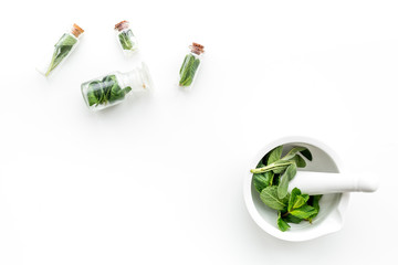 Herbal medicine. Herbs in mortar bowl and in small bottles on white background top view copy space