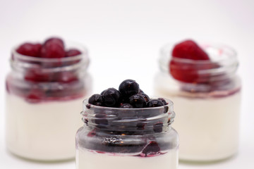 Fresh berries in the jar with the yogurt. On white background.