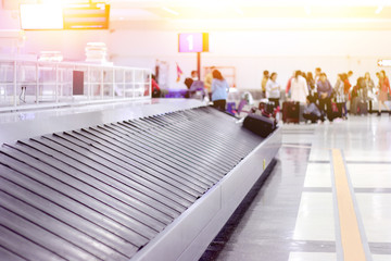 empty baggage conveyor belt at the airport with blurred waiting passenger background
