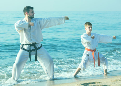 Man and teenager perform exercises on karate