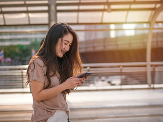 Young asian woman using smartphone searching for social media in the city.