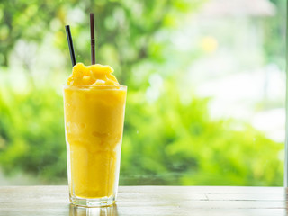 Mango smootie with green background on wood table