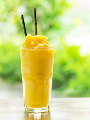 Mango smootie with green background on wood table