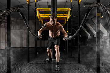 Man working out with battle ropes at gym