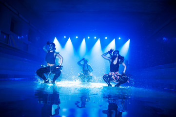 Performance on the water of a dance group against the background of club light.