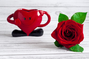 Czerwona róża na drewnianym biaym stole z ozdobnym serduszkiem © Bea