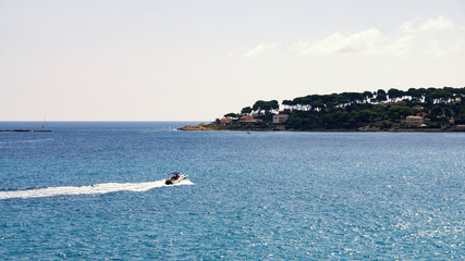 Boat driving on sea in front of coast at sunset on C&ocirc;te d'azur