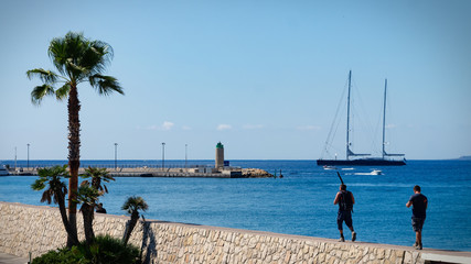 Two men walking on stone coast to go fishing at Côte d'azur