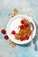 granola with dried apricots, raspberries and yogurt for breakfast, vertical top view