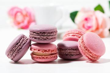 macaroon cookies and flowers on white table, closeup