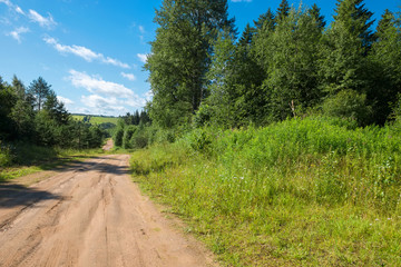 Fototapeta na wymiar Nice summer scene with track road turn near green Falevsky mounds