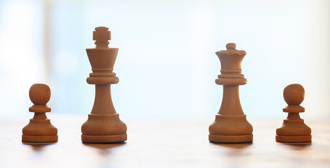Chess pieces light brown color. Close up view of king, queen, pawns with details. Blur backdrop.
