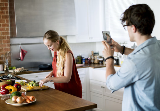 Man taking a photo of his wife in the kitchen