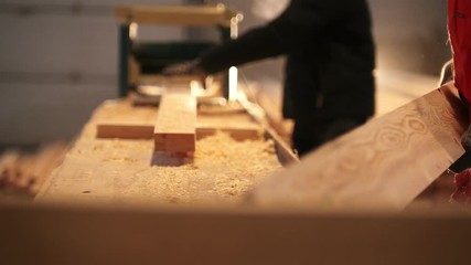 Workers control process of sawing and polishing wooden boards at the sawmill
