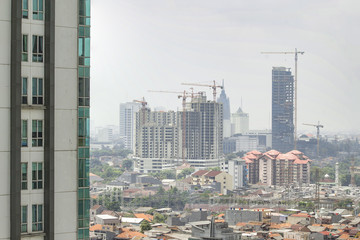 Fototapeta premium Construction progress on booming south-east asian highrise housing market. Construction cranes and highrise residential buildings on the rise.