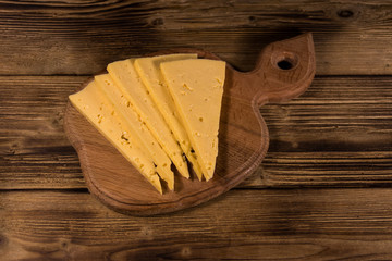 Fototapeta na wymiar Sliced cheese on cutting board on wooden table