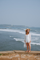 Girl in a hat and sunglasses on a background of waves.  Sri Lanka