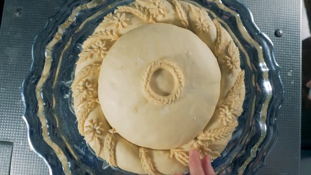 An unbaked round bread during decoration in a close view. 
