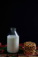A glass bottle with fresh milk and a piece of cookie and peanut on the table