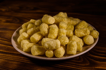 Ceramic plate with corn sticks on wooden table