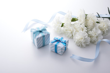 青色のギフトボックスと白いカーネーションとリボン