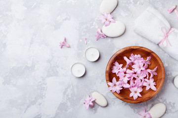 Aromatherapy, spa, beauty background with massage pebble, perfumed flowers water and candles on stone table top view. Relaxation and zen like concept. Flat lay style.