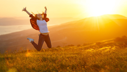 Happy woman jumping and enjoying life  at sunset in mountains