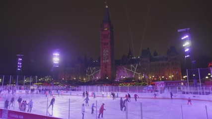 People Ice Skating at Canadian Parliament in Ottawa with Canada 150 Projected on Peace Tower