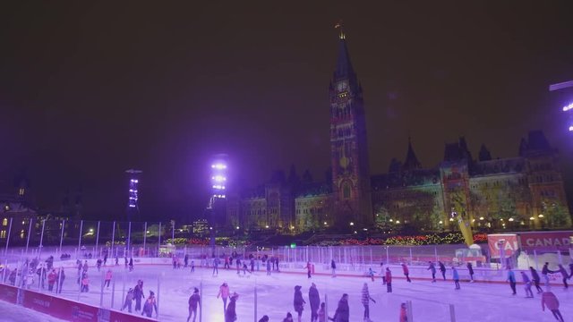 Pan of People Ice Skating at Parliament in Ottawa with Northern Lights Show in Background